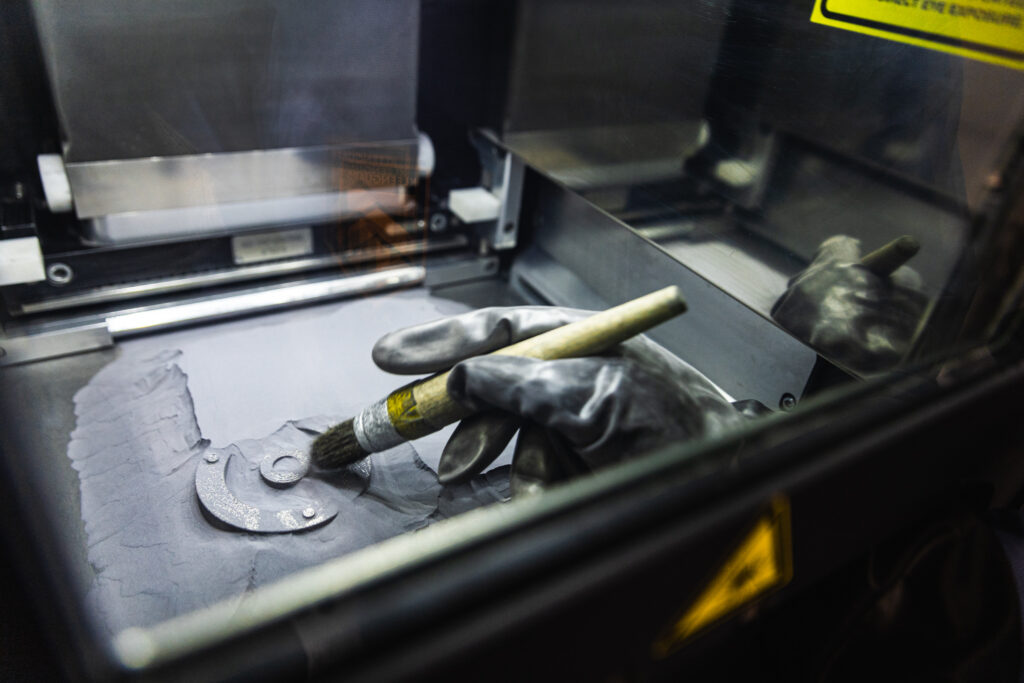 Brush handling of metal powder in an additive manufacturing machine